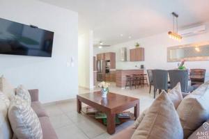 a living room with a couch and a table and a kitchen at Spacious home with private yard and community pool in La Paz
