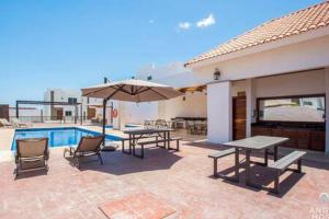 a patio with tables and an umbrella next to a pool at Spacious home with private yard and community pool in La Paz