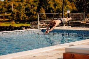 a man is diving into a swimming pool at Etno Villa Mokanji in Danilovgrad