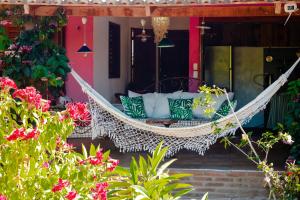 a hammock on the front porch of a house with flowers at Casa FLOREAL Icaraizinho de Amontada wifi in Icaraí