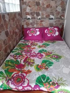 łóżko z różowymi poduszkami i narzutą kwiatową w obiekcie KANALU w mieście Bouillante