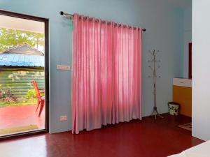 una habitación con una cortina rosa y una puerta en Marari Phoenix Beach Front Homestay, en Mararikulam