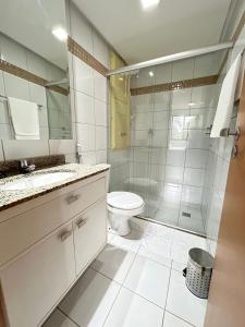 a white bathroom with a toilet and a shower at L209 Apto em resort beira lago com TV Smart in Brasilia