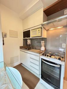 a kitchen with a stove and a microwave at L209 Apto em resort beira lago com TV Smart in Brasília