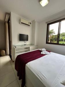 a bedroom with a bed and a desk and a window at L209 Apto em resort beira lago com TV Smart in Brasília