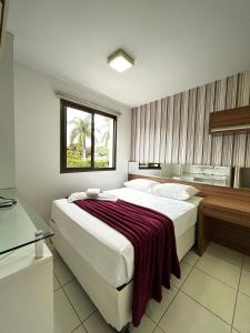 a bedroom with a large bed with a red blanket on it at L209 Apto em resort beira lago com TV Smart in Brasilia