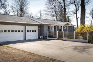 a house with a fence and a driveway at Upscale Urban Oasis: Spacious & Chic with Hot Tub! in Traverse City