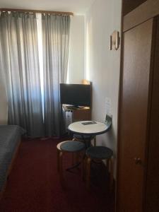 a small room with a table and two stools and a television at Hotel Zum Weissen Mohren in Walluf