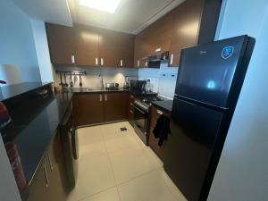 uma grande cozinha com um frigorífico preto em Dinar Home em Abu Dhabi