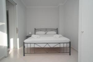 uma cama com lençóis brancos e almofadas num quarto em Alonaki home em Mesaíon Karlovásion
