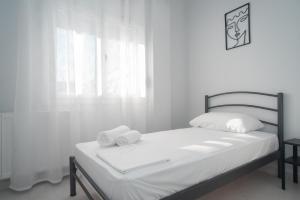 um quarto branco com uma cama com toalhas em Alonaki home em Mesaíon Karlovásion