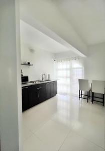 cocina blanca con fregadero, mesa y sillas en Secret View en Isabela