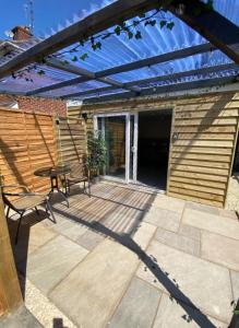 a wooden patio with a pergola and a table at The Studios in Hempstead