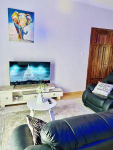 sala de estar con sofá y TV en Cyda Orchid Home-Buziga-Munyonyo, en Kampala