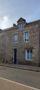 un edificio de ladrillo con una puerta y ventanas azules en DU SEL A LA VIE, grand studio entre marais et océan, en Batz-sur-Mer