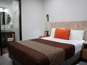 een slaapkamer met een bed met een oranje kussen en een wastafel bij Hotel Mayis in Oaxaca City