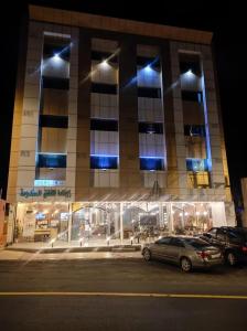 um edifício com carros estacionados num parque de estacionamento à noite em هوتيل المجاردة em Al Majaridah