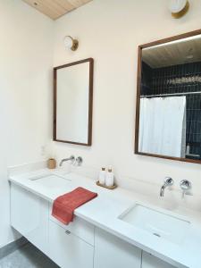 a white bathroom with two sinks and a mirror at Modern waterfront cottage +hot tub in Marion Bridge