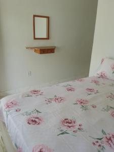 Una cama con una manta blanca con flores rosas. en Suíte Sunflower 103 en Rio das Ostras