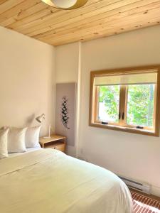 a bedroom with a white bed and a window at Modern waterfront cottage +hot tub in Marion Bridge