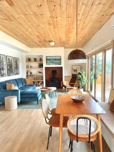 a living room with a blue couch and a table at Modern waterfront cottage +hot tub in Marion Bridge