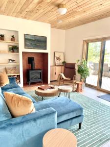 a living room with a blue couch and a fireplace at Modern waterfront cottage +hot tub in Marion Bridge