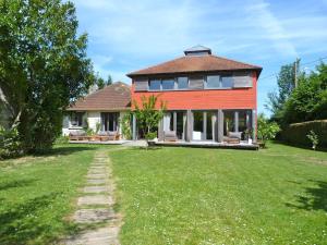 ein großes rotes Haus mit einem Rasenplatz in der Unterkunft Maison d'architecte idéalement située pour les JO in Neauphle-le-Château