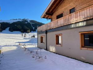 un edificio con nieve en el suelo delante de él en Luxusapartment mit Sauna am Berg en Sankt Ulrich am Pillersee