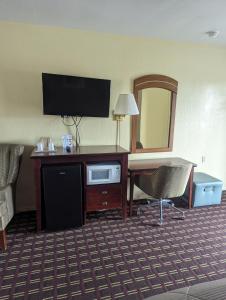 um quarto de hotel com uma secretária com uma televisão e um computador em Dollar Inn em Somerset
