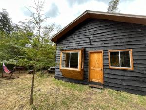 uma pequena cabana com duas janelas e uma árvore em Cabañas Maco em Ranco