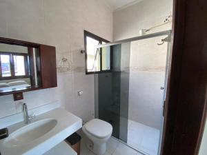 a bathroom with a toilet and a sink and a shower at Casa do Bert in Itanhaém