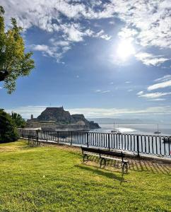 a row of benches sitting on the grass near the water at olivegrove in Sidari