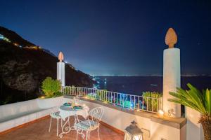 - un balcon avec une table et des chaises la nuit dans l'établissement Villa Poesia, à Praiano