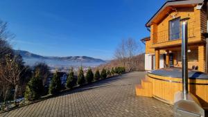 a wooden house with a balcony and a road at La casa din deal in Vişeu de Sus