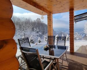 a table and chairs on a porch with snow covered trees at La casa din deal in Vişeu de Sus