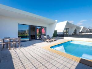 ein Haus mit einem Pool, einem Tisch und Stühlen in der Unterkunft Villas Cardás in Sanxenxo