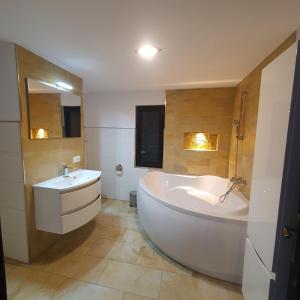 a large white bathroom with a tub and a sink at La casa din deal in Vişeu de Sus
