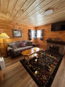 - un salon avec un canapé et une table dans l'établissement Rowe's Adirondack Cabins of Schroon Lake, à Schroon Lake