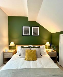 a bedroom with green walls and a bed with a yellow pillow at Charming home near Gatwick Airport in Crawley