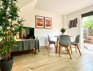 uma sala de estar com uma mesa e cadeiras e uma televisão em Charming home near Gatwick Airport em Crawley