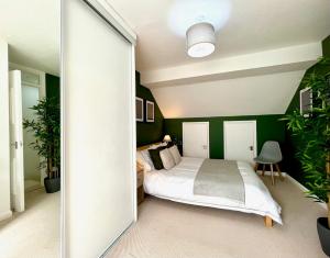 a bedroom with a bed and green walls at Charming home near Gatwick Airport in Crawley