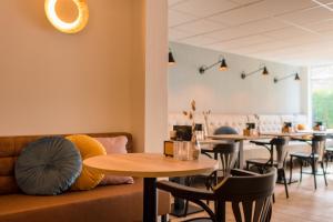 un restaurante con mesas y sillas y un sofá en Hotel-Brasserie De Walvisvaarder en Hollum