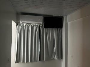 ein Zimmer mit einem Vorhang und einem Fernseher an der Decke in der Unterkunft Hotel Delavy in Chapecó