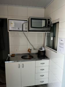 una pequeña cocina con microondas y fregadero en Hotel Delavy, en Chapecó