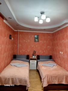 two beds in a room with orange walls at Подобова оренда двокімнатної квартири Старичі in Starychi