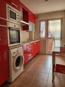 a kitchen with red cabinets and a washing machine at Apto. Vista Bahía Santander in Pontejos