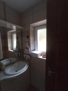 een badkamer met een wastafel en een raam bij Pele vendégház in Velem