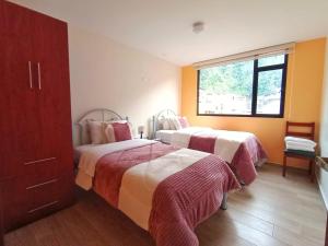 ein Hotelzimmer mit 2 Betten und einem Fenster in der Unterkunft Hospedaje Charlie's House in Baños