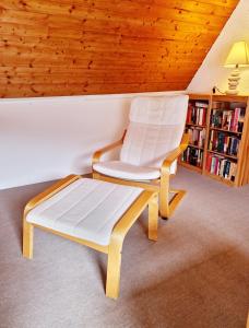 einen weißen Stuhl in einem Zimmer mit Bücherregal in der Unterkunft Ferienwohnung Naturoase Quasthoff in Neustadt an der Weinstraße