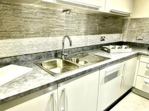 una cucina con lavello in acciaio inossidabile e armadietti bianchi di Exclusive Marina View Apartment Free Parking a Cardiff